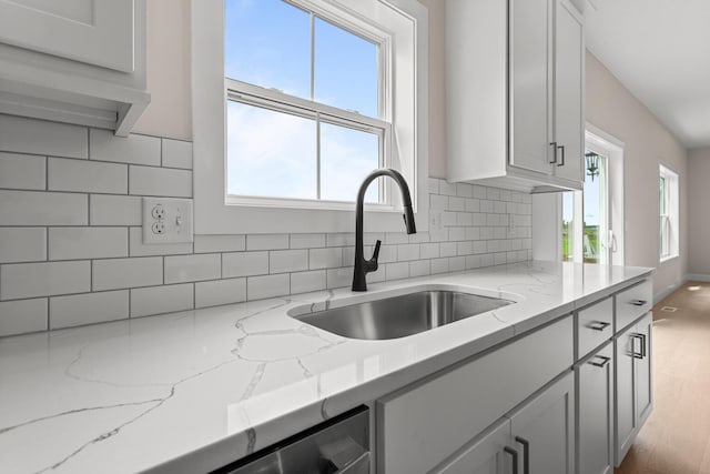 605 Wheatley Dr, Mahomet, IL 61853 - kitchen featuring a sink, tasteful backsplash, light stone counters, wood finished floors, and baseboards
