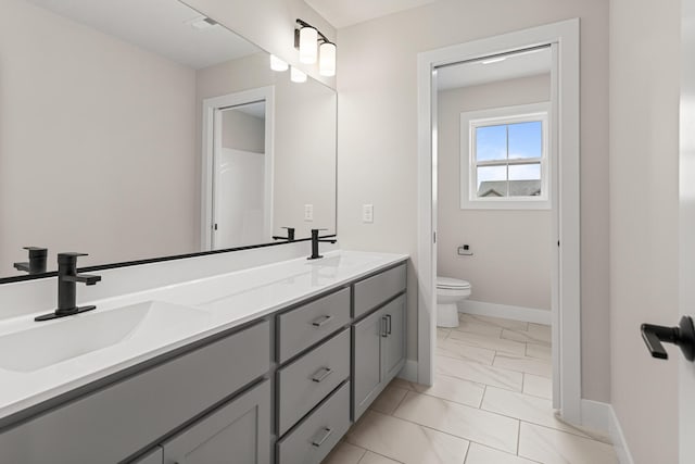 605 Wheatley Dr, Mahomet, IL 61853 - bathroom featuring double vanity, toilet, marble finish floors, and baseboards