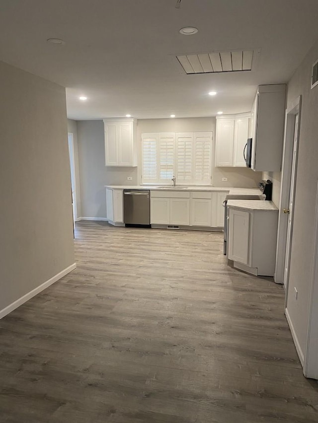 kitchen with dark wood-style floors, white cabinets, a sink, and stainless steel dishwasher