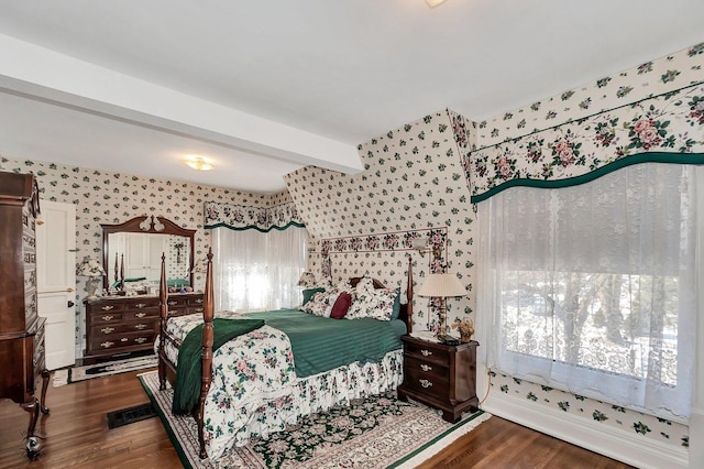 bedroom with beamed ceiling, wood finished floors, and wallpapered walls