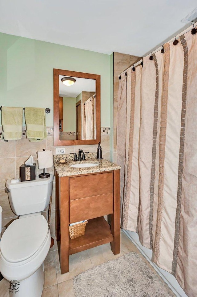 bathroom featuring toilet, a shower with shower curtain, vanity, tile walls, and tile patterned floors