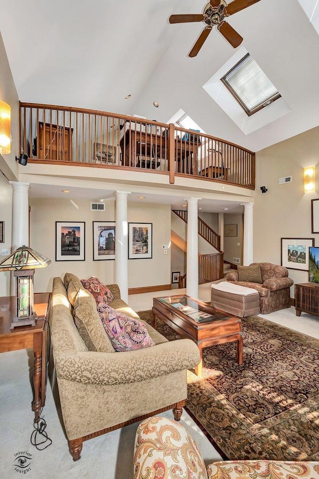 living room with high vaulted ceiling, visible vents, a ceiling fan, stairs, and decorative columns