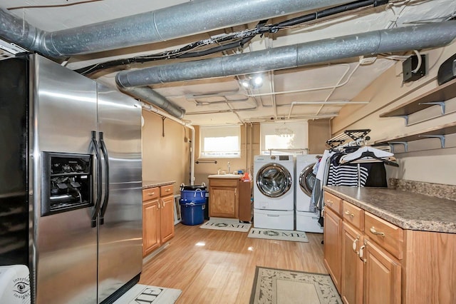 laundry area with a sink, light wood finished floors, cabinet space, and independent washer and dryer