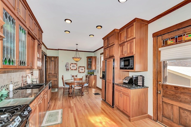 kitchen featuring built in appliances, a sink, light wood-type flooring, dark stone counters, and brown cabinetry