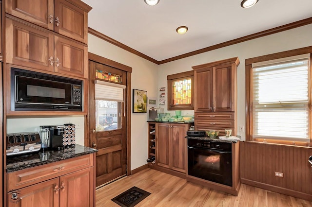 kitchen featuring visible vents, brown cabinetry, dark stone countertops, crown molding, and black microwave