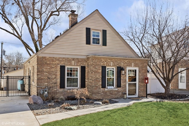 view of front of property featuring brick siding, a chimney, a front lawn, and fence