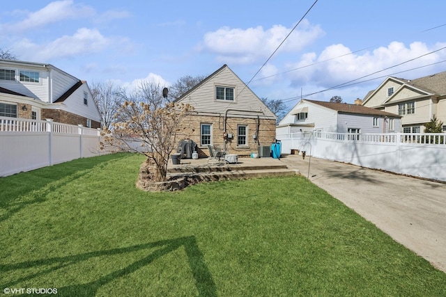 rear view of property with a patio area, central air condition unit, a lawn, and a fenced backyard