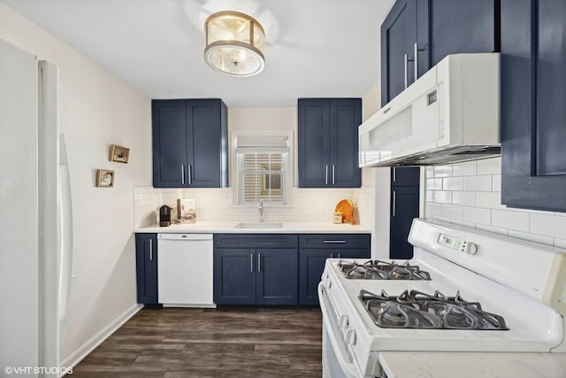 kitchen with white appliances, blue cabinets, light countertops, and a sink