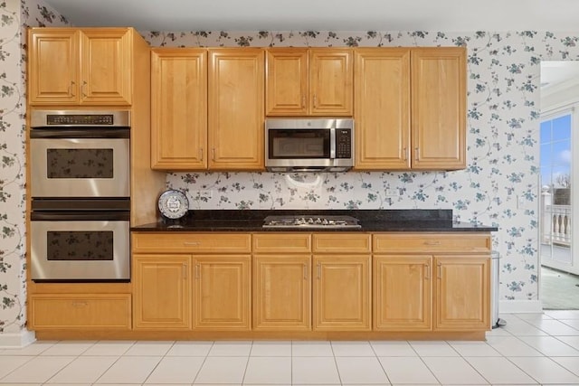 kitchen featuring wallpapered walls, light tile patterned floors, baseboards, and stainless steel appliances