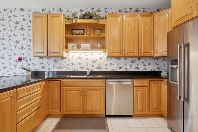 kitchen featuring light tile patterned floors, appliances with stainless steel finishes, a sink, and wallpapered walls