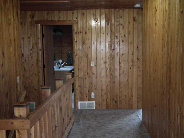 carpeted spare room with visible vents and wooden walls