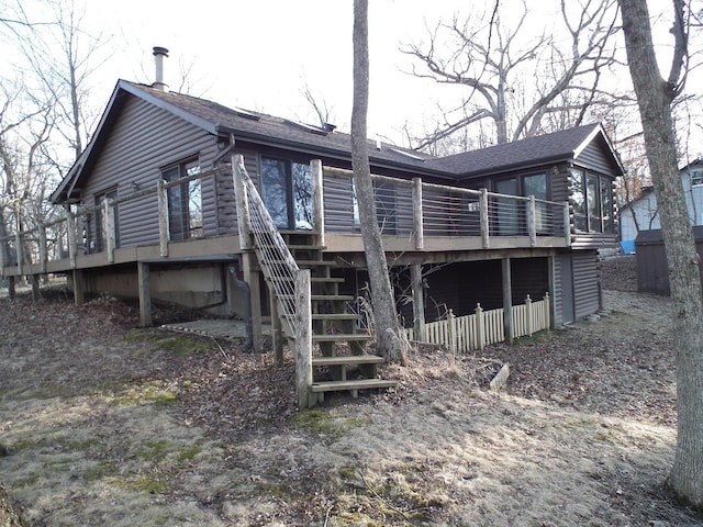 rear view of house with stairs, a deck, a shingled roof, and log siding