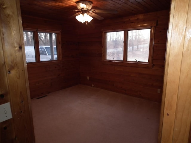 spare room featuring plenty of natural light, wood walls, carpet, and wood ceiling