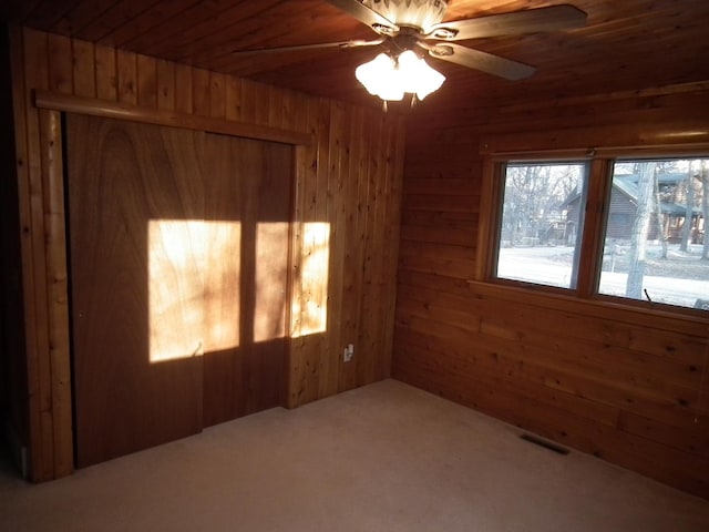 spare room with visible vents, wood ceiling, ceiling fan, carpet, and wood walls