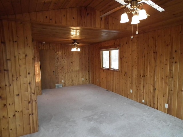 carpeted empty room featuring wood ceiling, visible vents, ceiling fan, and wooden walls