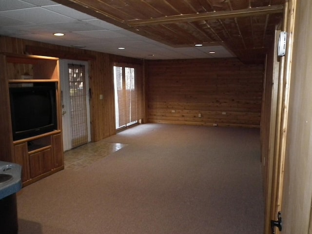 unfurnished living room featuring carpet and wooden walls