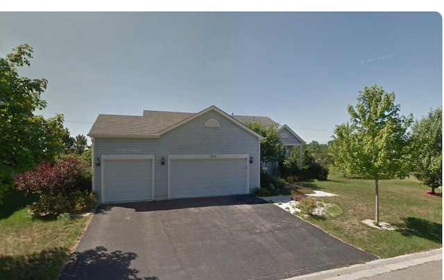 view of front of house featuring driveway, an attached garage, and a front yard