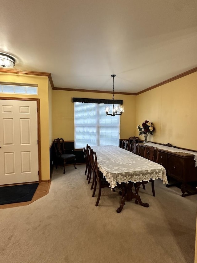 dining room with a notable chandelier, ornamental molding, and light colored carpet