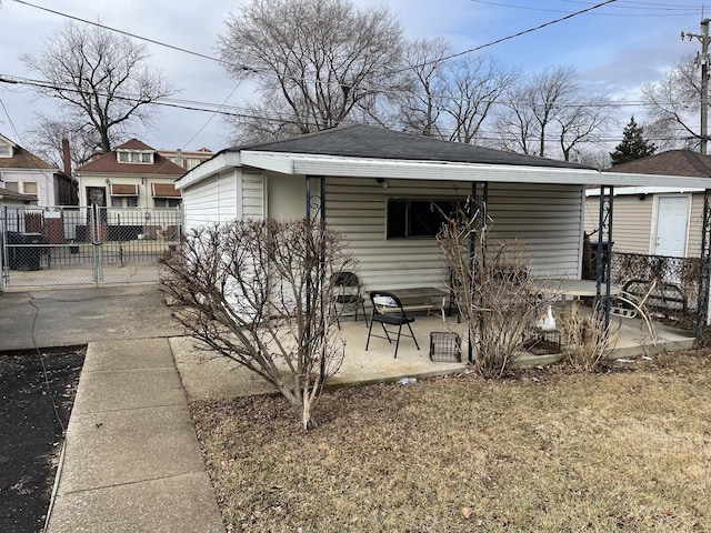 rear view of house featuring roof with shingles, a patio, and fence