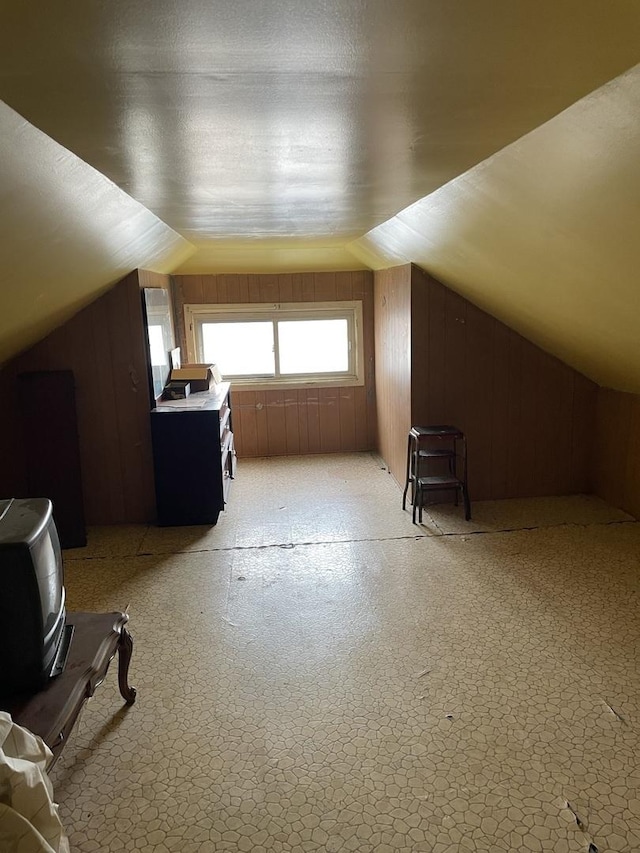 bonus room with lofted ceiling, wood walls, and light floors