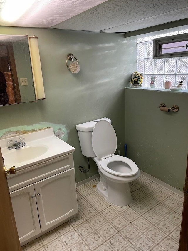 bathroom featuring toilet, baseboards, and vanity