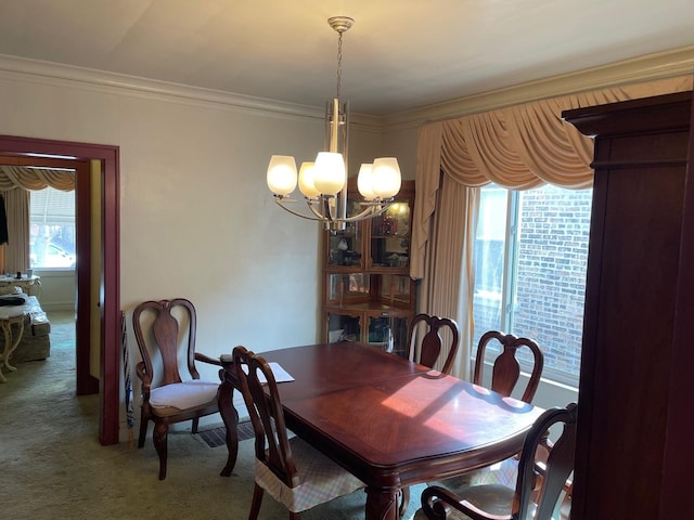 carpeted dining room with a chandelier and crown molding