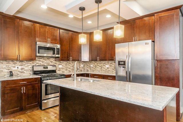 kitchen with decorative backsplash, light wood-style flooring, light stone counters, appliances with stainless steel finishes, and a sink