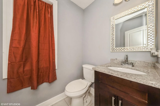 bathroom with toilet, vanity, baseboards, and tile patterned floors