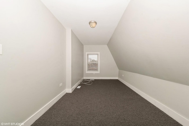 bonus room with vaulted ceiling, dark colored carpet, and baseboards