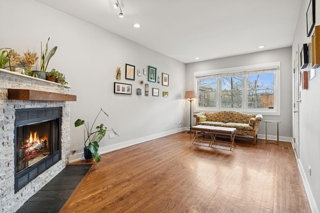 living area featuring recessed lighting, baseboards, wood-type flooring, and a fireplace