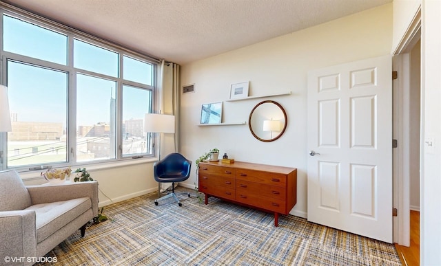 living area featuring visible vents, a textured ceiling, and baseboards