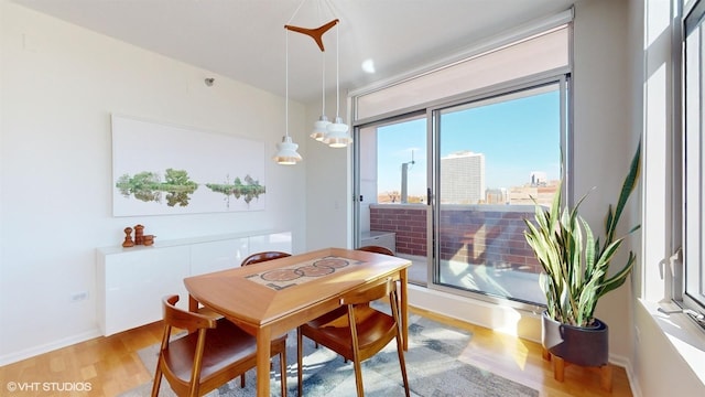 dining area featuring baseboards, light wood-style floors, and a city view