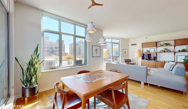 dining area featuring visible vents, light wood-style flooring, and baseboards