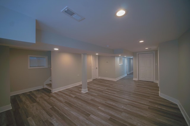 finished below grade area featuring baseboards, stairs, visible vents, and dark wood-type flooring