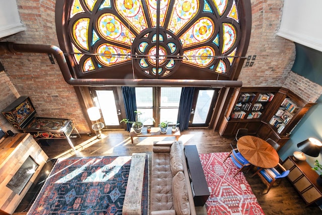 living room featuring brick wall, a high ceiling, and wood finished floors