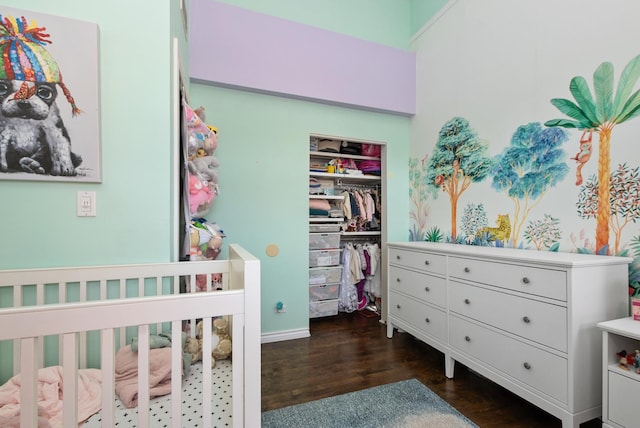 bedroom with a nursery area, a closet, and dark wood finished floors