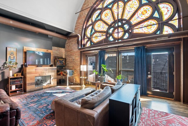 living area with high vaulted ceiling, a large fireplace, and wood finished floors