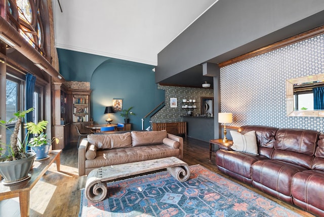 living area featuring wallpapered walls, crown molding, an accent wall, and wood finished floors