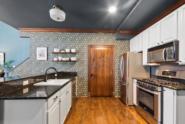 kitchen with dark wood-style floors, appliances with stainless steel finishes, a sink, and white cabinetry