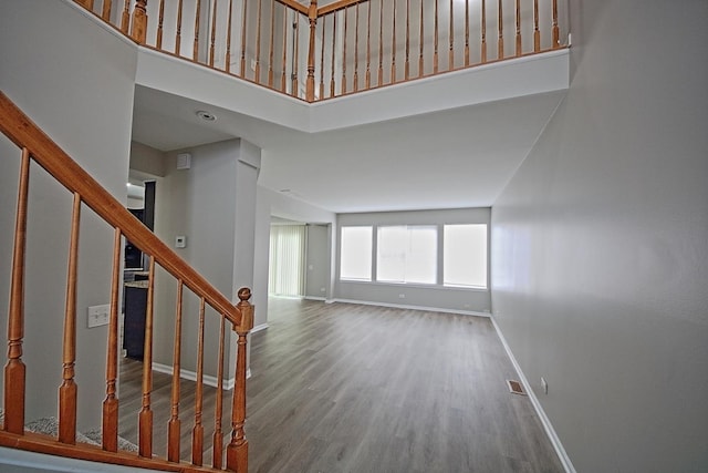 interior space with a high ceiling, visible vents, baseboards, and wood finished floors