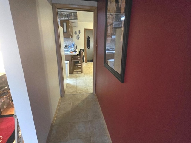 hallway featuring baseboards and tile patterned floors