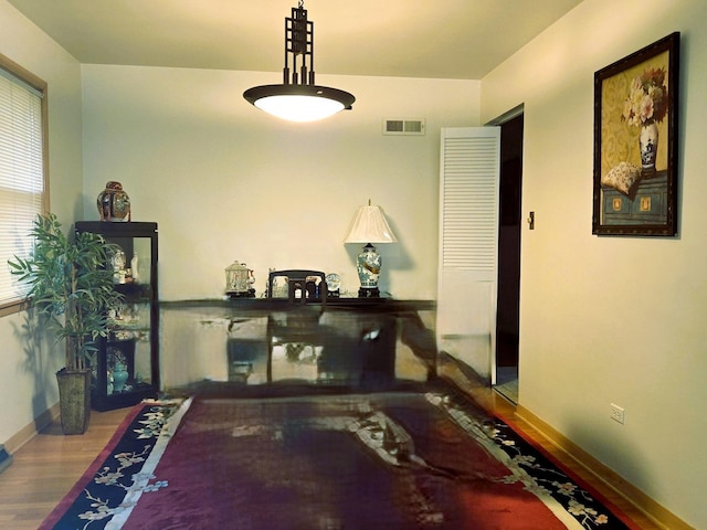 hallway featuring baseboards, visible vents, and wood finished floors