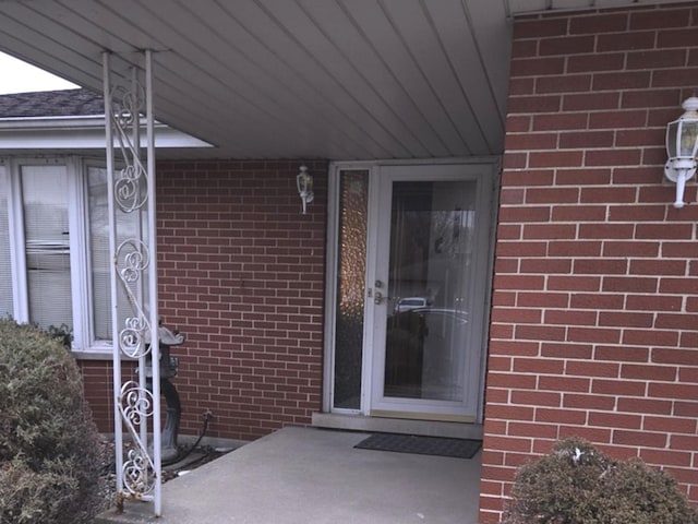 view of exterior entry featuring brick siding