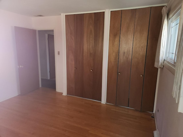 unfurnished bedroom with two closets and wood finished floors