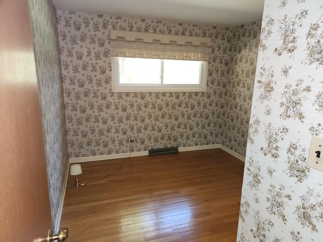 unfurnished room with wallpapered walls, hardwood / wood-style flooring, baseboards, and visible vents