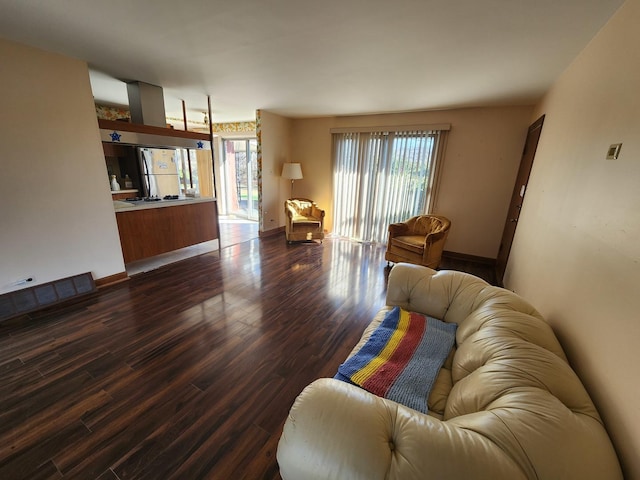 living room featuring dark wood-style floors, baseboards, and a wealth of natural light