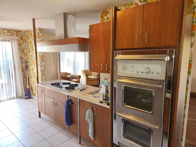 kitchen with wallpapered walls, oven, white gas cooktop, and island range hood