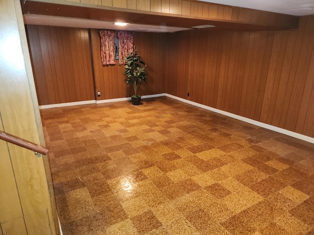 finished basement with tile patterned floors, baseboards, and wood walls