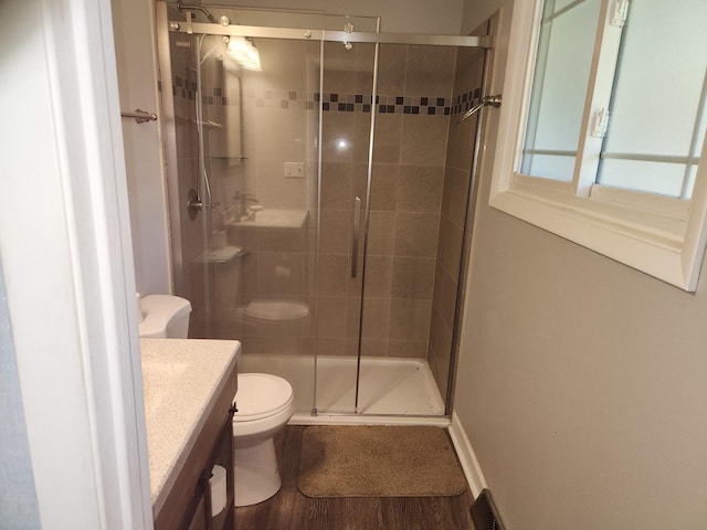 full bath featuring a shower stall, baseboards, toilet, wood finished floors, and vanity