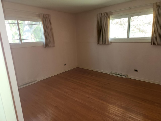 empty room featuring visible vents, baseboards, and wood finished floors